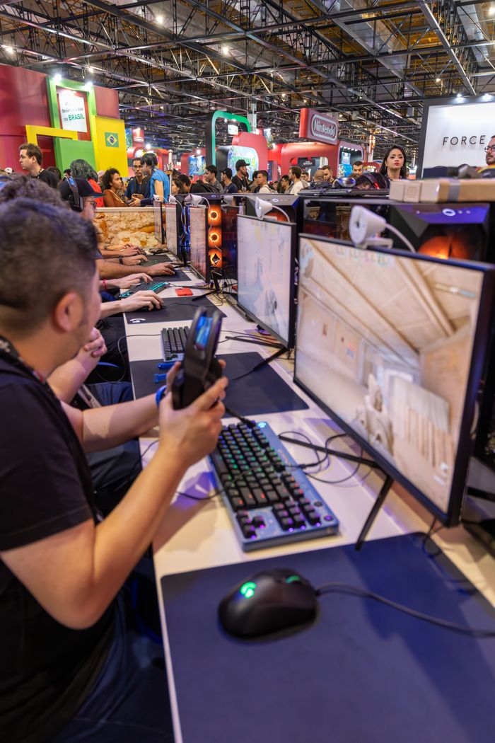 Services A vibrant gaming convention featuring players engaged with computers and gaming accessories.