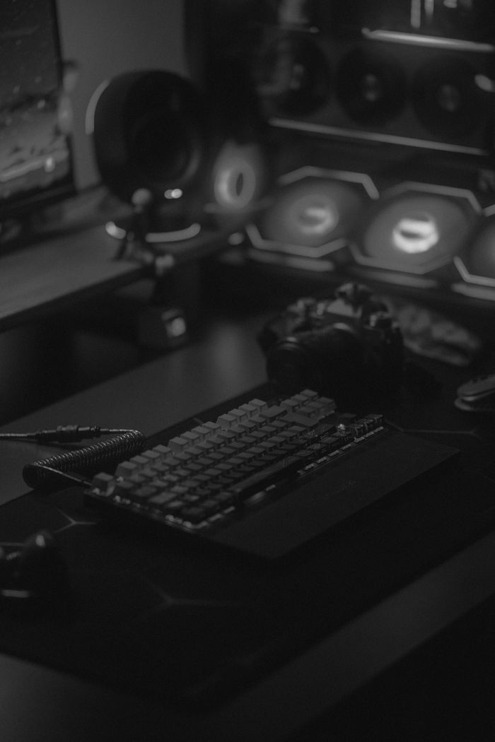 Services A dimly lit gaming PC setup with mechanical keyboard and headphones, perfect for gamers.