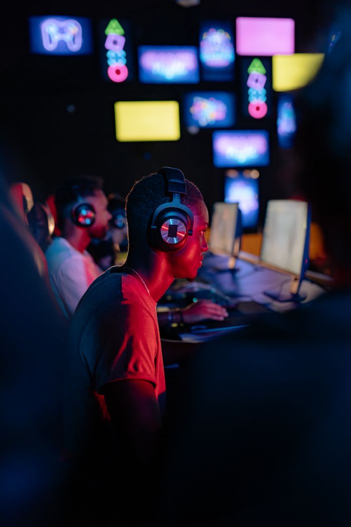 Crafting Captivating Headlines: Your awesome post title goes here African American man gaming intensely on computer with headphones in vibrant setting.